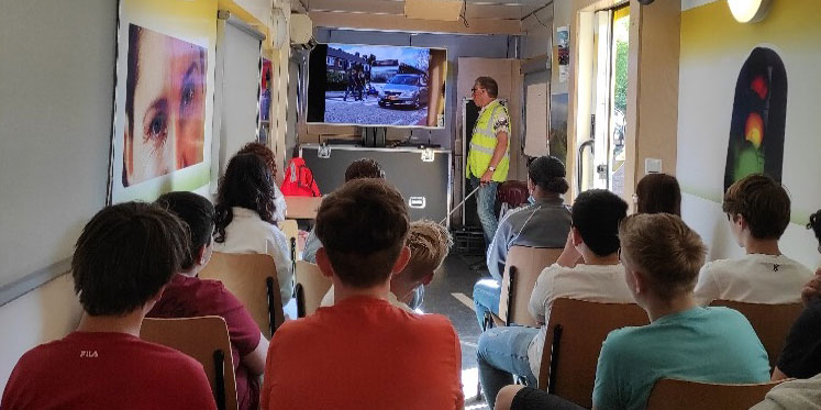 Beeld bekeken vanuit de klas, waarbij docent voor een scherm staat en verkeerssituatie uitlegt.